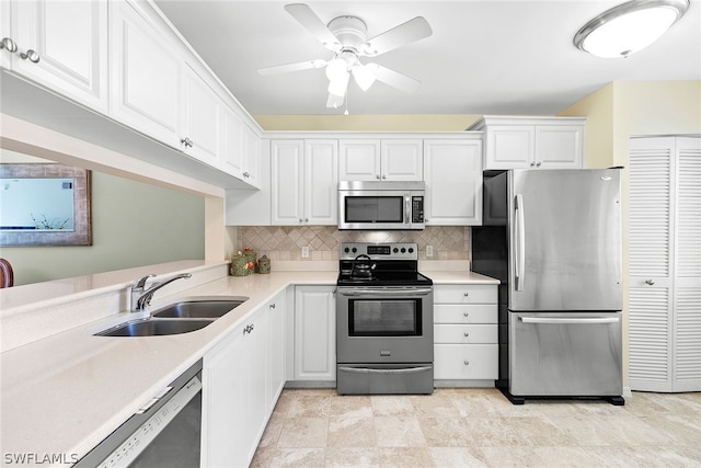 kitchen with stainless steel appliances, white cabinets, decorative backsplash, sink, and ceiling fan