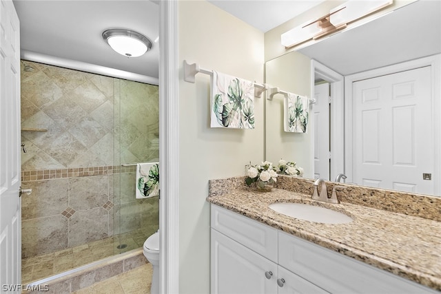 bathroom with a shower with door, vanity, toilet, and tile patterned floors