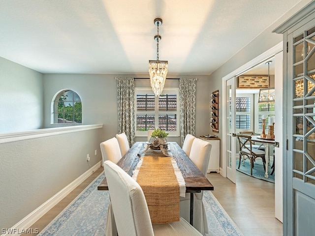 dining space with a healthy amount of sunlight, an inviting chandelier, and light hardwood / wood-style flooring