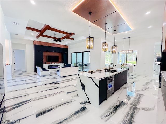 kitchen featuring sink, hanging light fixtures, coffered ceiling, a center island with sink, and ceiling fan with notable chandelier