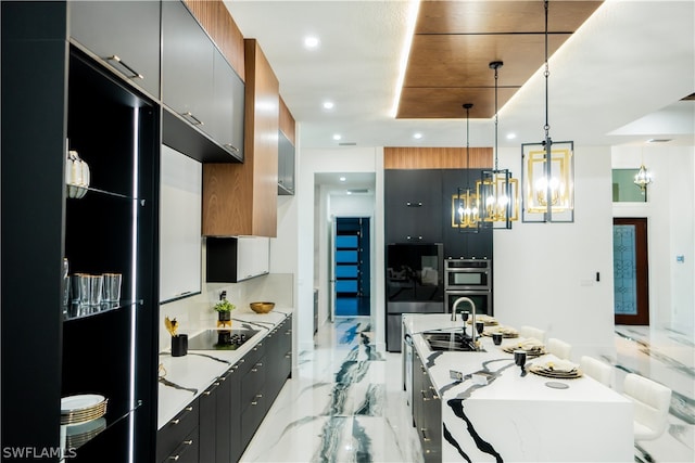 kitchen featuring black appliances, a center island with sink, sink, hanging light fixtures, and a chandelier