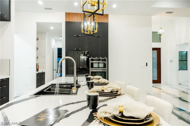 kitchen featuring black refrigerator, sink, hanging light fixtures, double oven, and a chandelier