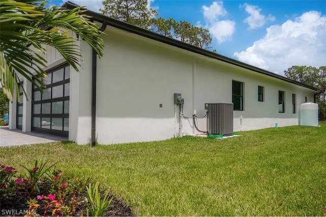 view of side of property featuring a yard and central AC unit