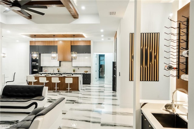 kitchen with beam ceiling, sink, a center island, backsplash, and pendant lighting