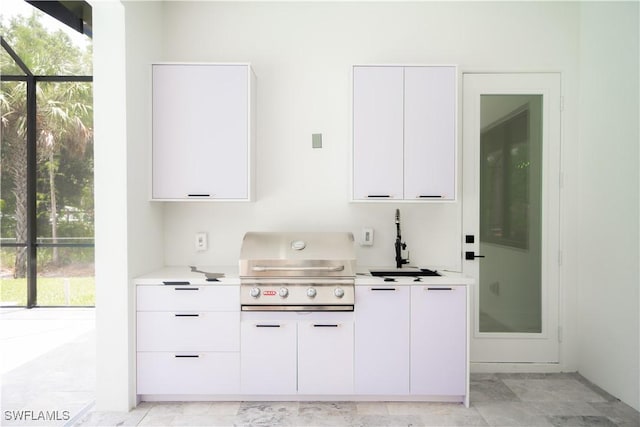 bar featuring white cabinets, a healthy amount of sunlight, and sink