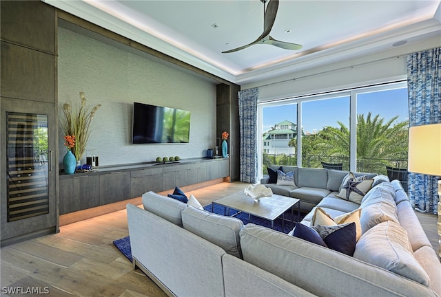 living room featuring ceiling fan, a tray ceiling, and hardwood / wood-style flooring