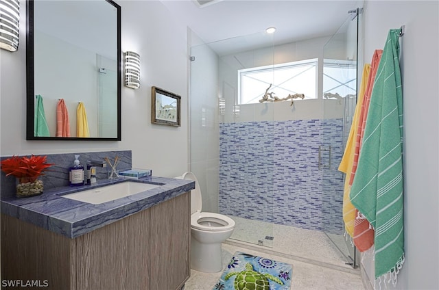 bathroom featuring a tile shower, tile flooring, vanity, and toilet