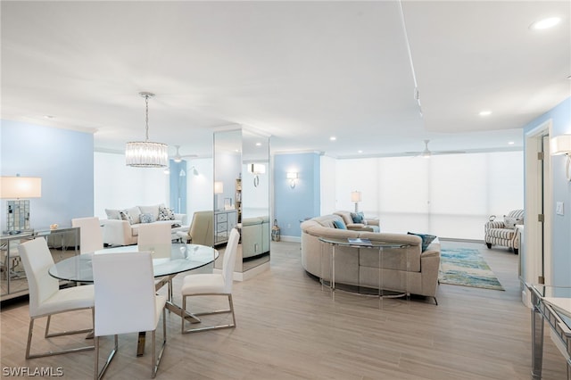 dining area with ceiling fan with notable chandelier and light hardwood / wood-style floors