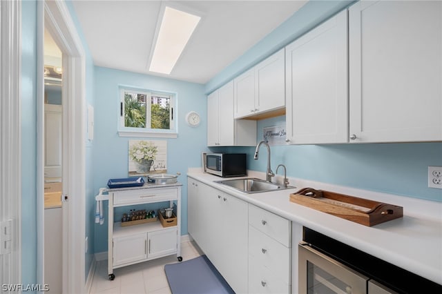 kitchen with sink, white cabinets, beverage cooler, and light tile patterned floors