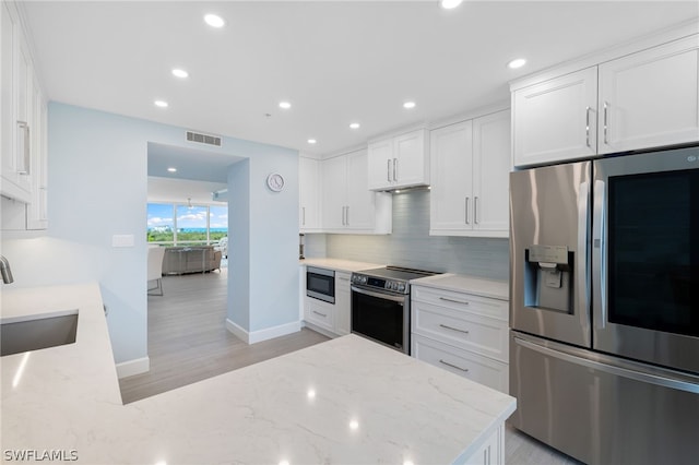 kitchen with tasteful backsplash, stainless steel appliances, light stone countertops, white cabinets, and sink