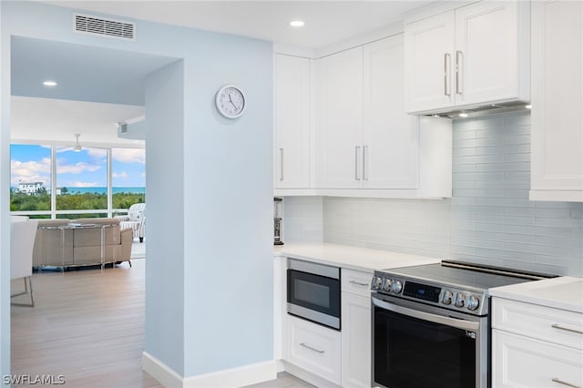 kitchen with white cabinetry, light wood-type flooring, stainless steel appliances, and decorative backsplash