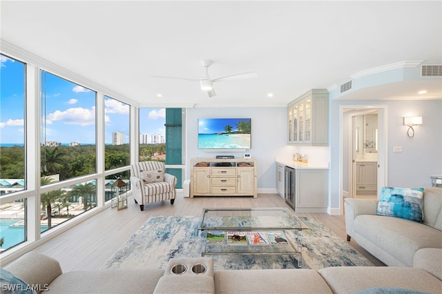 living room featuring beverage cooler, a wall of windows, light hardwood / wood-style floors, ceiling fan, and bar area