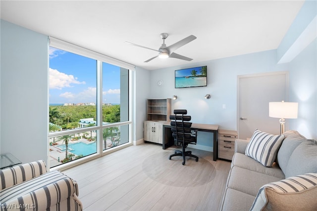 home office featuring light hardwood / wood-style flooring, ceiling fan, and floor to ceiling windows