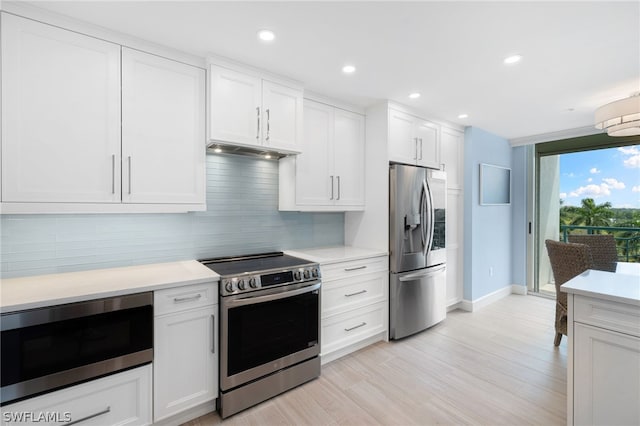 kitchen with white cabinets, appliances with stainless steel finishes, light hardwood / wood-style flooring, and tasteful backsplash