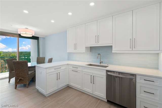 kitchen featuring stainless steel dishwasher, decorative backsplash, sink, white cabinetry, and kitchen peninsula