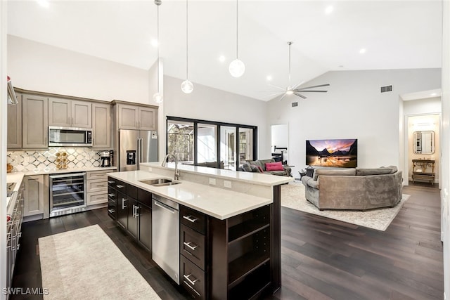 kitchen with wine cooler, sink, tasteful backsplash, a center island with sink, and appliances with stainless steel finishes