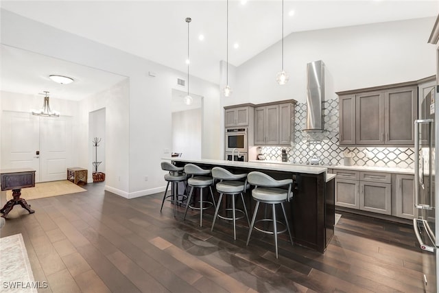 kitchen with pendant lighting, a center island, a breakfast bar area, and wall chimney range hood