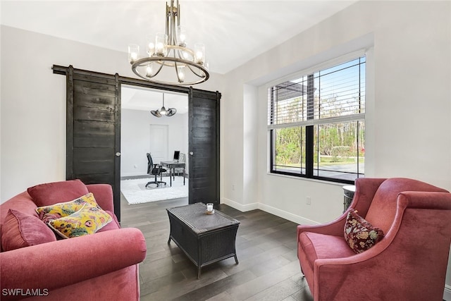 living area with a barn door, an inviting chandelier, and dark hardwood / wood-style flooring