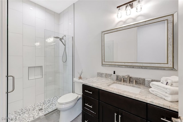 bathroom with vanity, toilet, and a shower with door