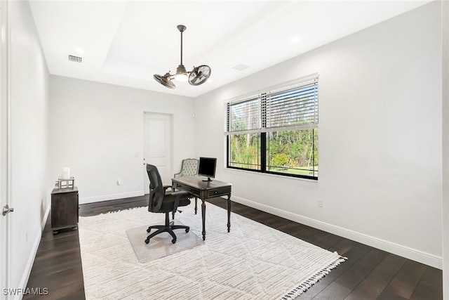 office area with dark wood-type flooring, a tray ceiling, and a chandelier