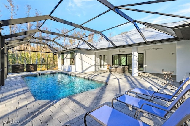 view of pool featuring an outdoor living space, ceiling fan, glass enclosure, and a patio