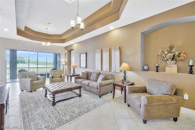 tiled living room with a raised ceiling and a chandelier