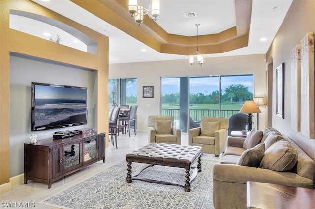 living room with a high ceiling, light tile patterned floors, a tray ceiling, and a chandelier