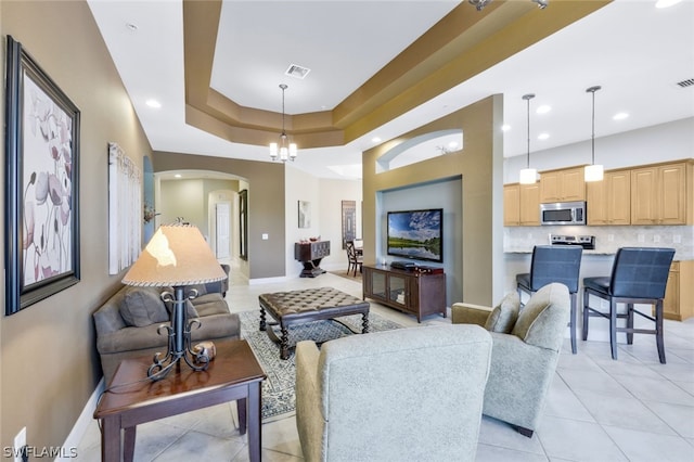 living room with a tray ceiling and a chandelier