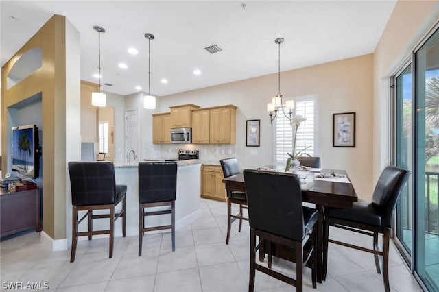 tiled dining room with a notable chandelier and sink