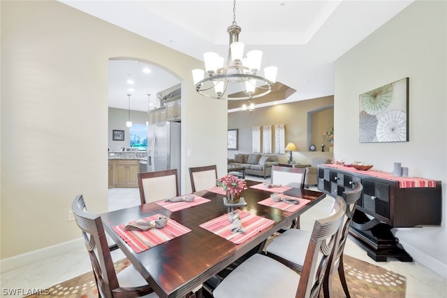 dining space featuring light tile patterned floors, a healthy amount of sunlight, a tray ceiling, and a notable chandelier