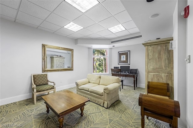 living room featuring a drop ceiling and baseboards