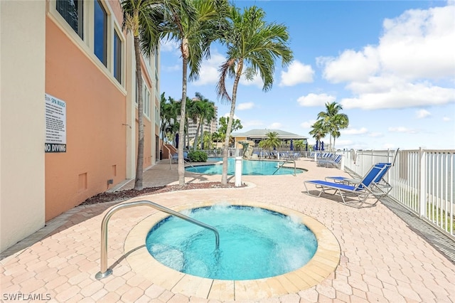 community pool with fence, a hot tub, and a patio