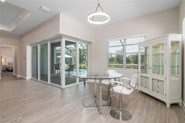 dining room with french doors, light hardwood / wood-style floors, and a raised ceiling