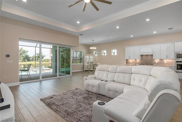 living room featuring a tray ceiling, ceiling fan, crown molding, and sink