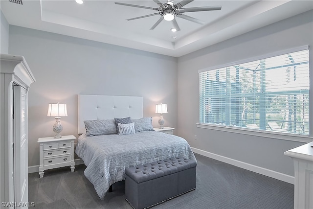 bedroom featuring multiple windows, a tray ceiling, and ceiling fan