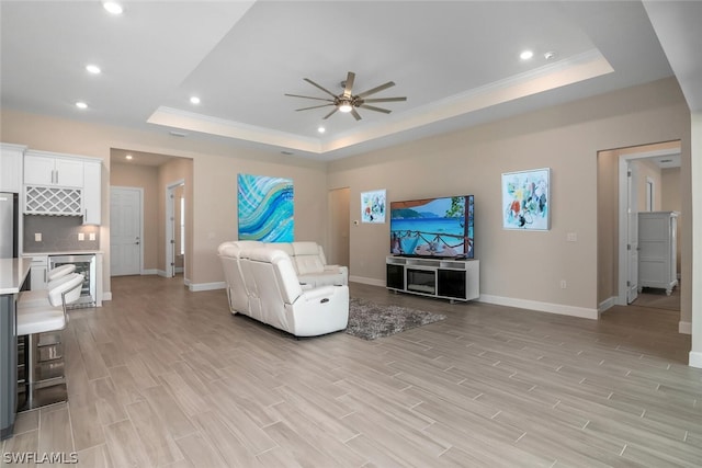 living room featuring ceiling fan, light hardwood / wood-style flooring, and a tray ceiling