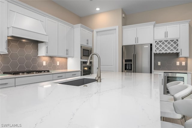 kitchen featuring light stone countertops, backsplash, a breakfast bar, stainless steel appliances, and white cabinets