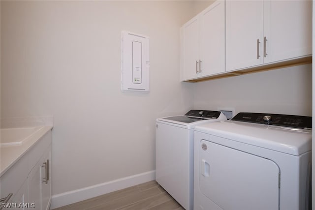 clothes washing area featuring washer and dryer, cabinets, light wood-type flooring, and sink