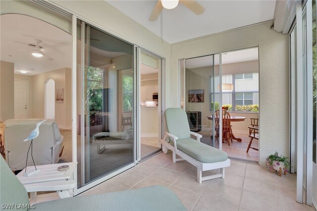 sunroom with arched walkways and ceiling fan