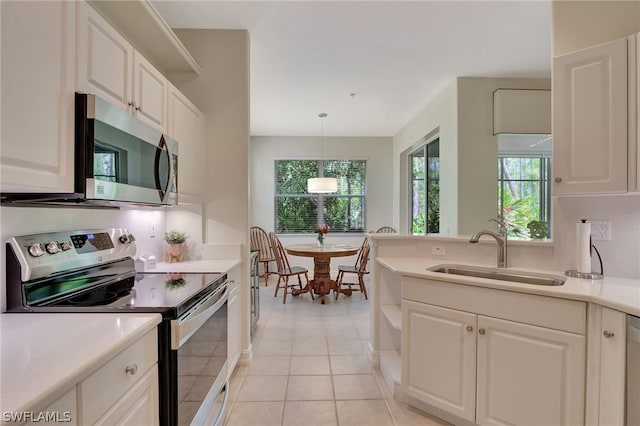 kitchen featuring white cabinetry, sink, hanging light fixtures, light tile patterned flooring, and appliances with stainless steel finishes