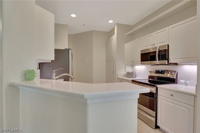 kitchen with kitchen peninsula, stainless steel appliances, and white cabinetry