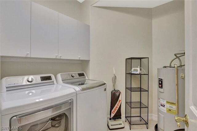 clothes washing area with washer and clothes dryer, cabinets, and water heater