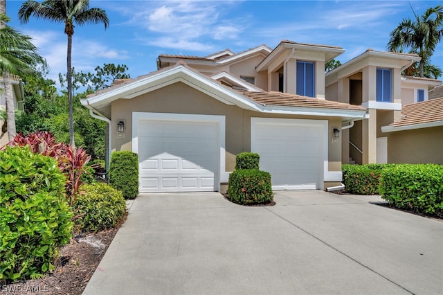 view of front facade with a garage, driveway, a tile roof, and stucco siding