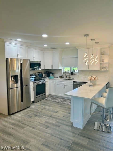 kitchen featuring stainless steel appliances, sink, white cabinetry, and kitchen peninsula