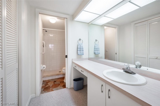 bathroom with vanity, toilet, and a tile shower