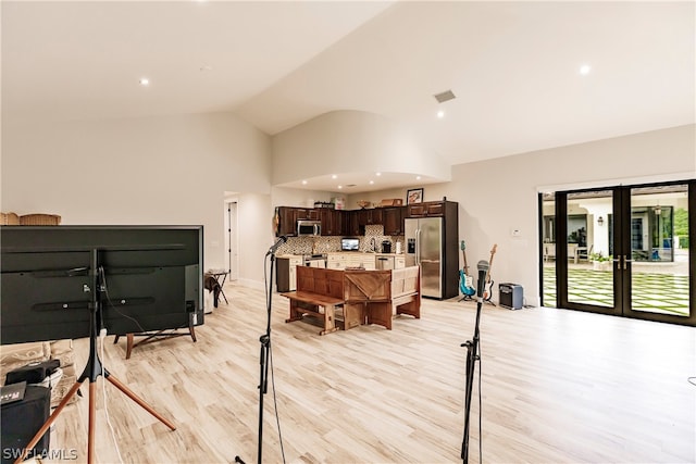 office space featuring high vaulted ceiling, french doors, and light hardwood / wood-style flooring