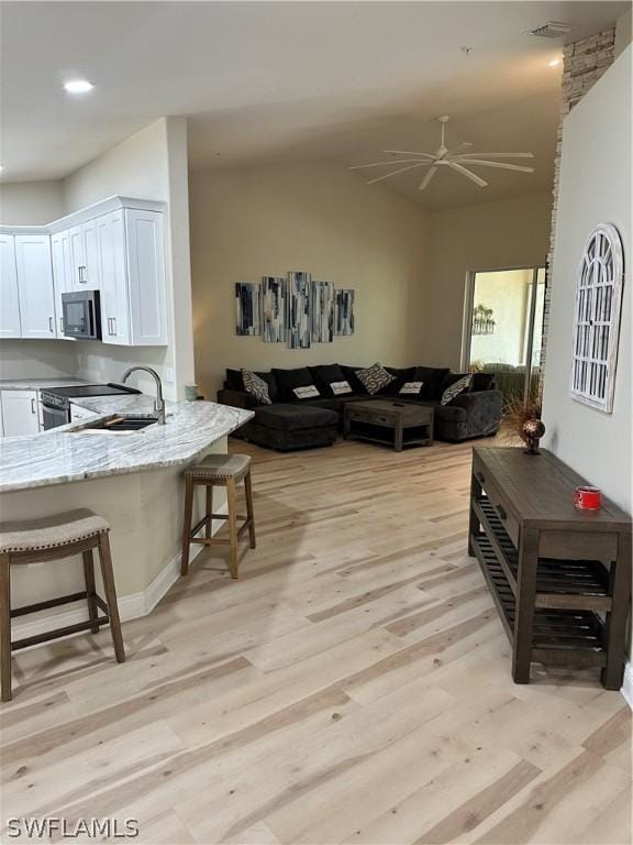 living room featuring ceiling fan, sink, and light wood-type flooring