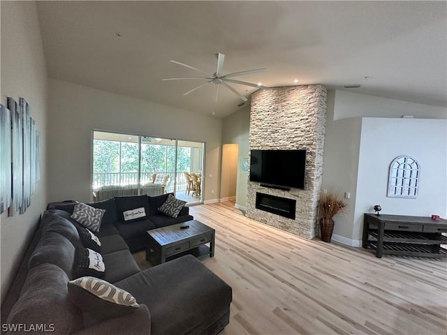 living room featuring vaulted ceiling, light wood-type flooring, ceiling fan, and a fireplace