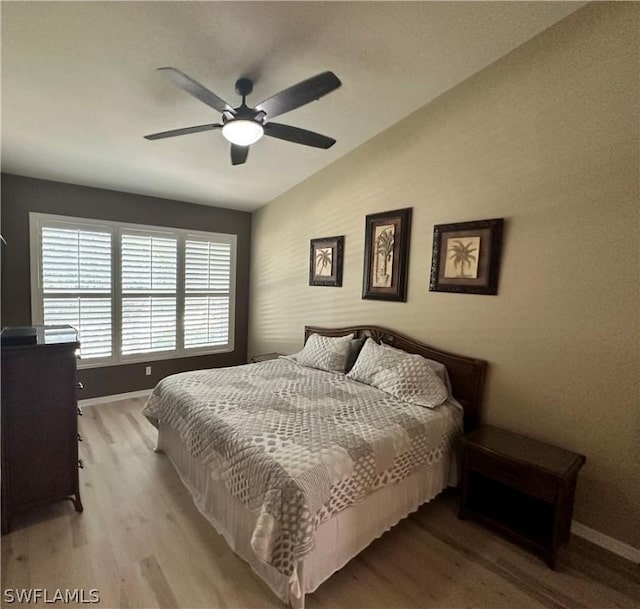 bedroom with light hardwood / wood-style flooring, vaulted ceiling, and ceiling fan