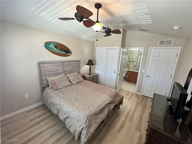 bedroom with lofted ceiling, ensuite bath, light hardwood / wood-style flooring, and a closet